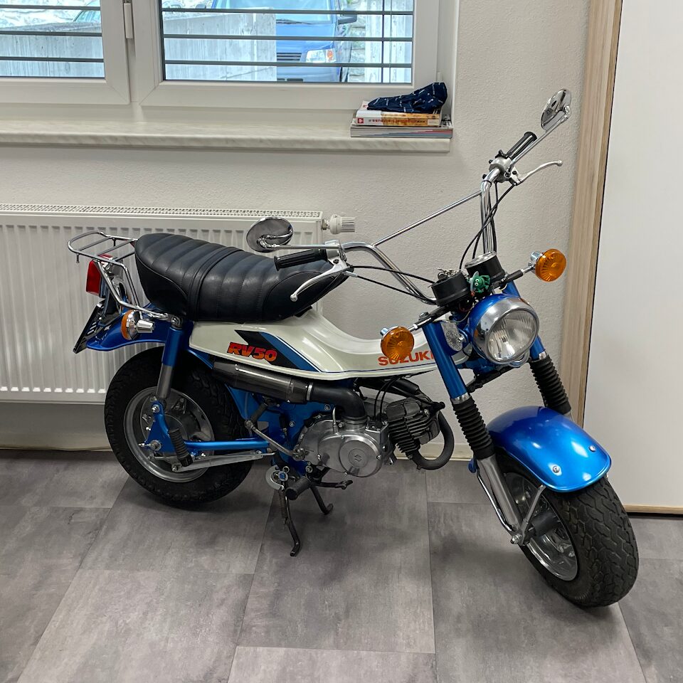 Ein blau-weißes Motorrad parkte vor einem Fenster.